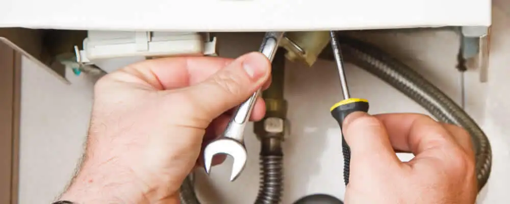 Boiler repair technician tightening pipe fittings and connections in Norton, MA