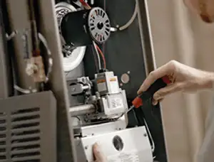 Furnace repair technician inspecting internal components and wiring in Norton, MA