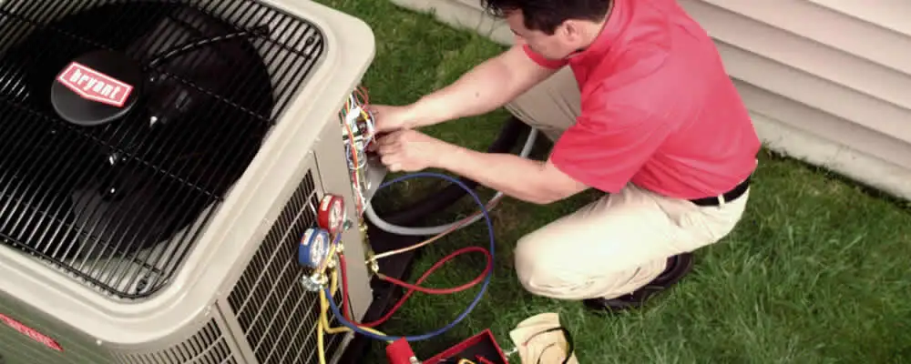 HVAC technician servicing an outdoor air conditioner unit in Norton, MA