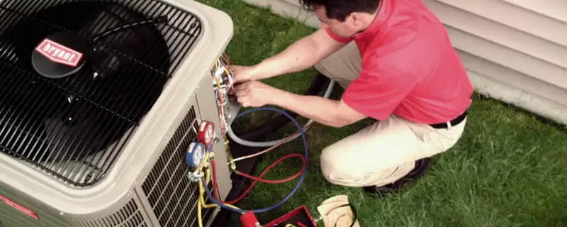 HVAC technician servicing an outdoor air conditioner unit in Norton, MA