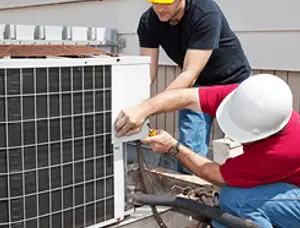 HVAC technicians repairing an outdoor AC unit on a rooftop in Norton, MA
