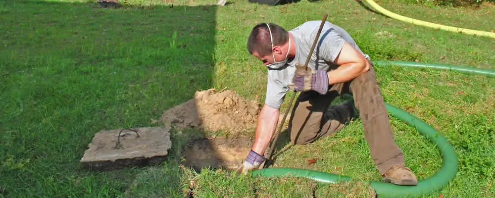 Septic pumping technician servicing a residential septic tank in Norton, MA