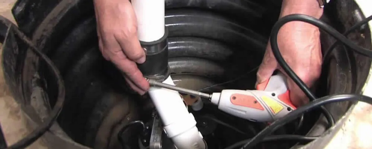 Sump pump installation technician connecting PVC discharge piping in Norton, MA