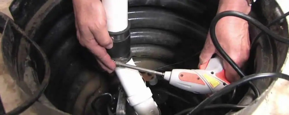Sump pump installation technician connecting PVC discharge piping in Norton, MA