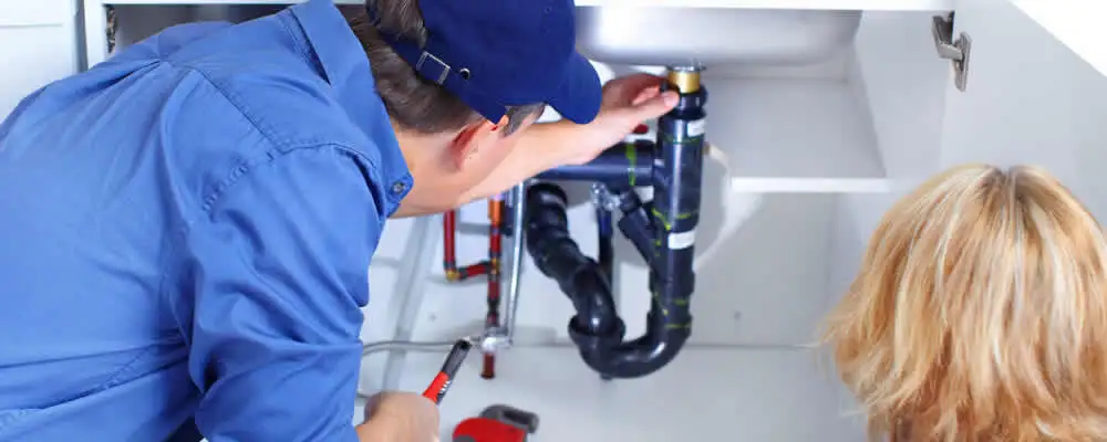 Plumber repairing under-sink drain pipes and fittings in Norton, MA